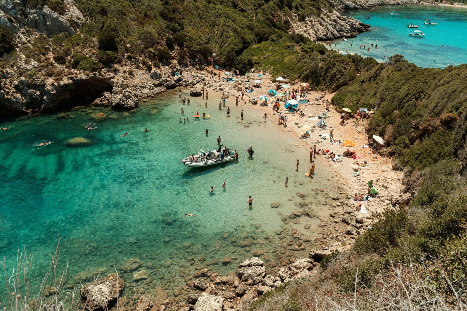 Crowded Mediterranean beach with azure water and people enjoying a sunny summer day.